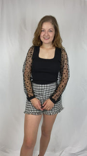 Black top with square neckline and polka dot mesh sleeves.